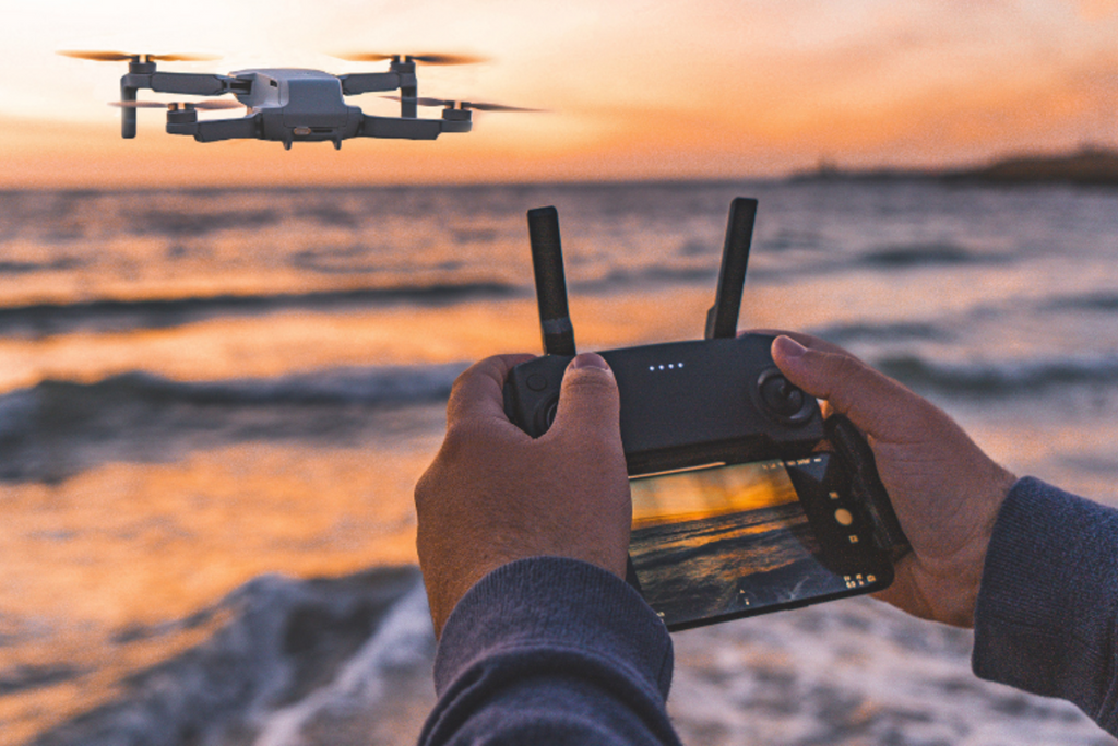 Drone pilot operating an aircraft with a remote controller during a practical flight.