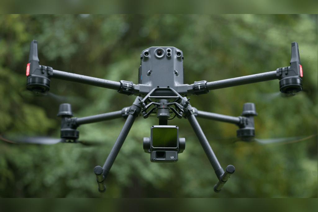 DJI Matrice 350 RTK carrying a Zenmuse L2 LiDAR payload over a wooded landscape.